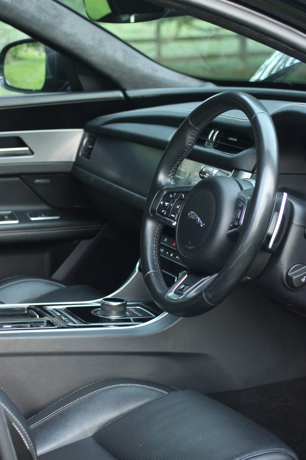 A vertical view of the Jaguar steering wheel, dashboard and interior trim.