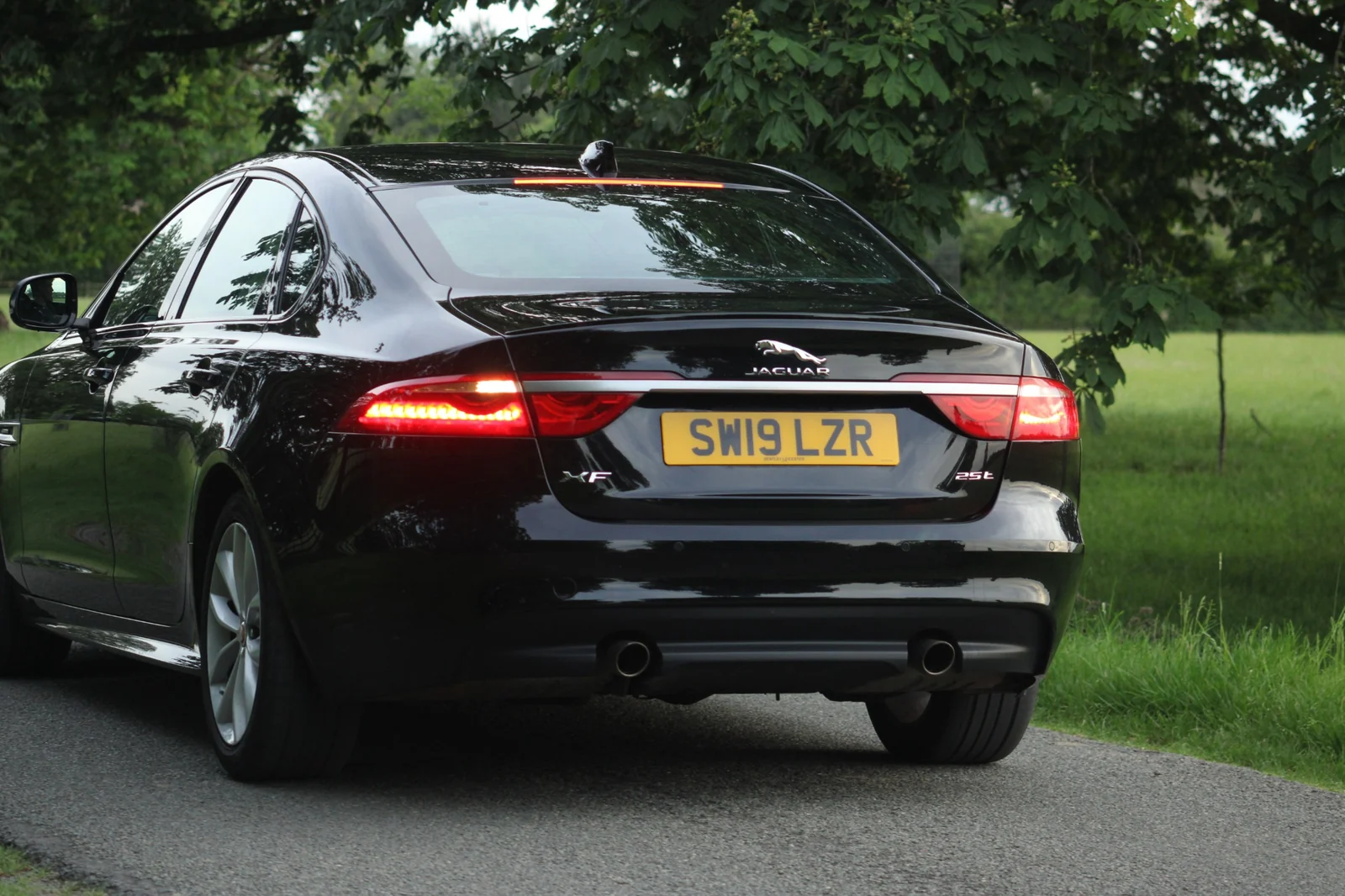 A close rear three-quarter view of a black Jaguar, with its rear lights illuminated.