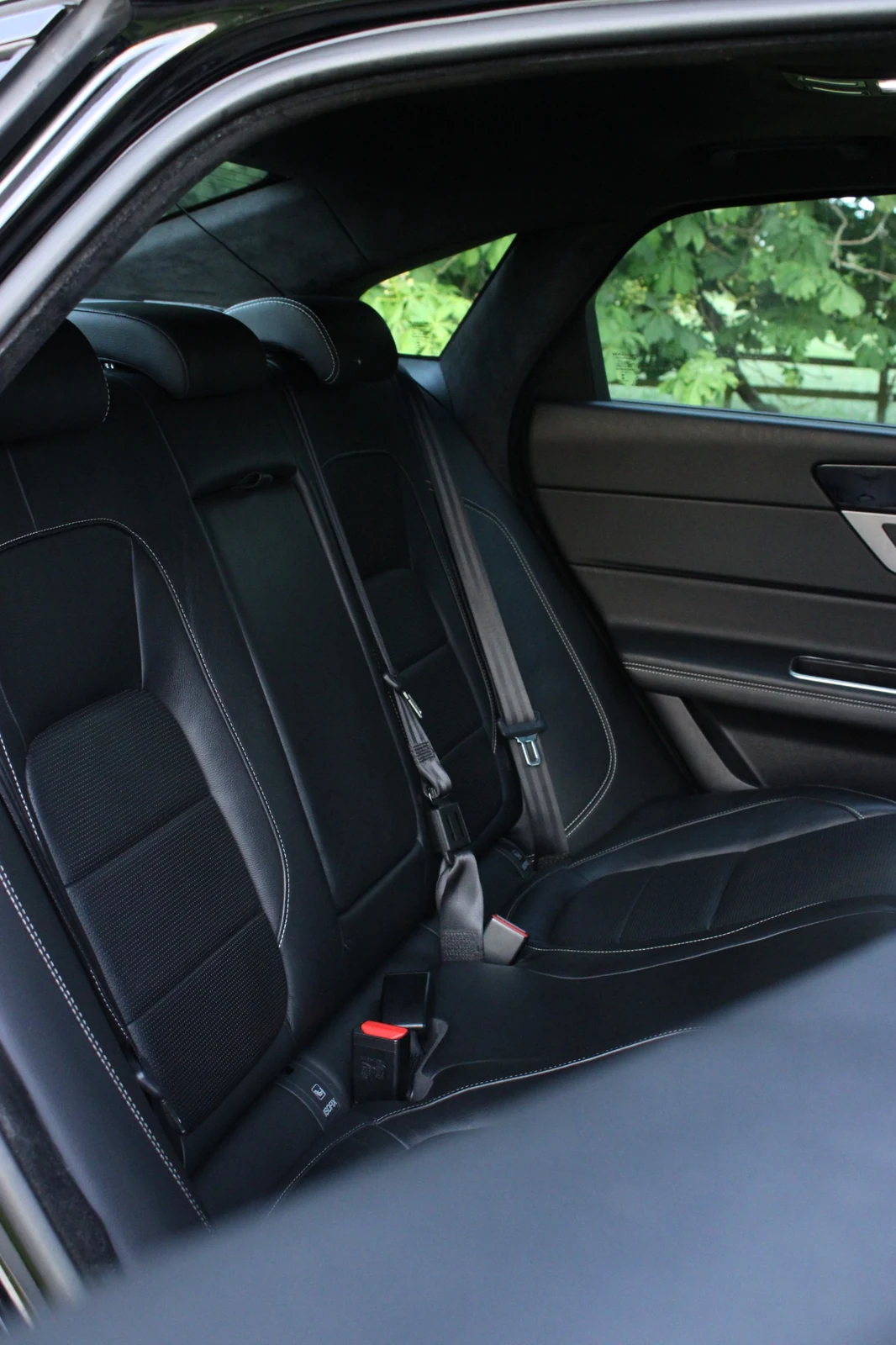 A vertical photograph of the Jaguar rear leather seats and cabin trim.