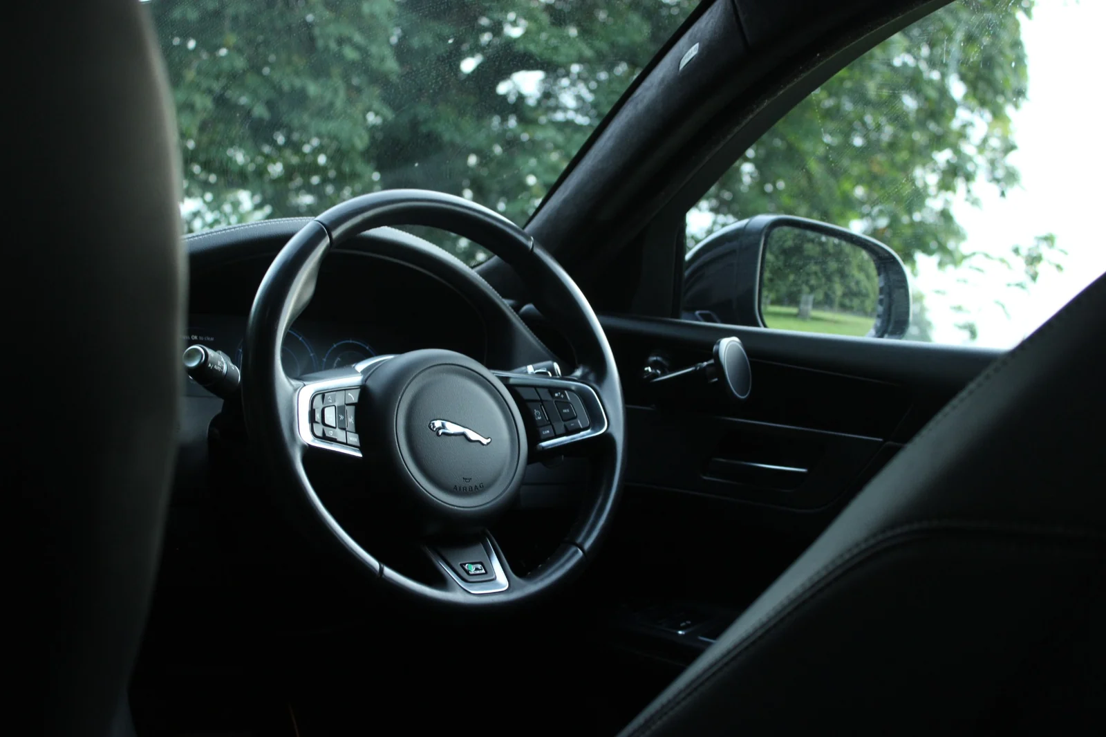 A Jaguar steering wheel and cockpit photographed through the front passenger side.